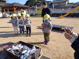 芋を火の中に入れる園児