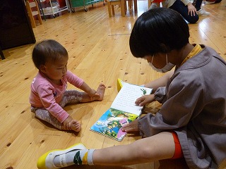 １歳児と一緒に絵本を見る５歳児