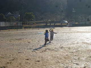 校庭で凧あげをする園児