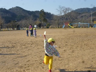 校庭で凧あげをする園児